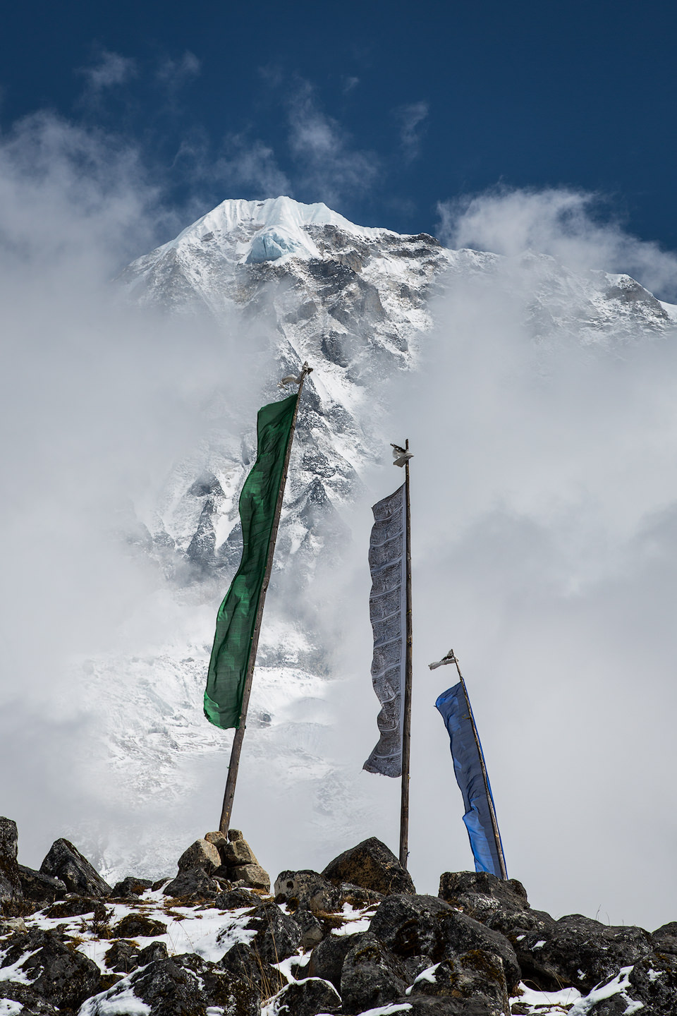 Prayer flags in the wind in front of himalayan peaks.