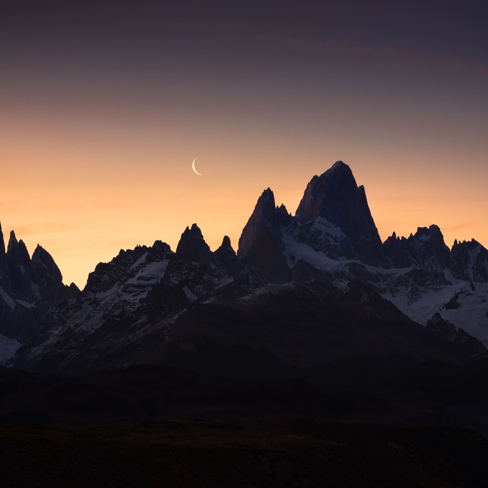 Crescent moon behind Cerro Torre and Fitz Roy at dusk